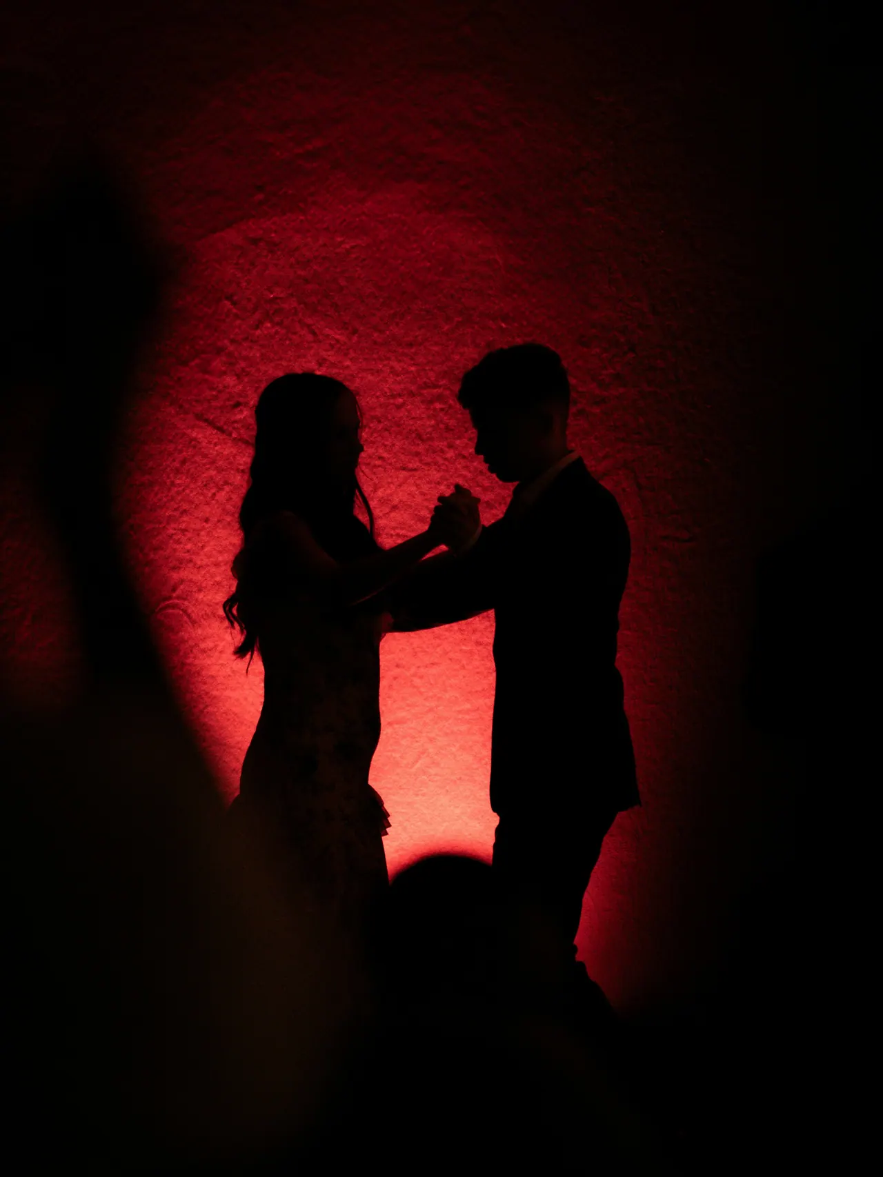 Silhouette eines tanzenden Paares vor rot beleuchteter Wand